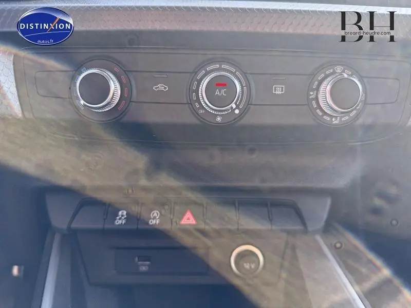 Vue rapprochée du tableau de bord de l'Audi A1 Sportback 2020, montrant les commandes de climatisation et les boutons de sécurité.