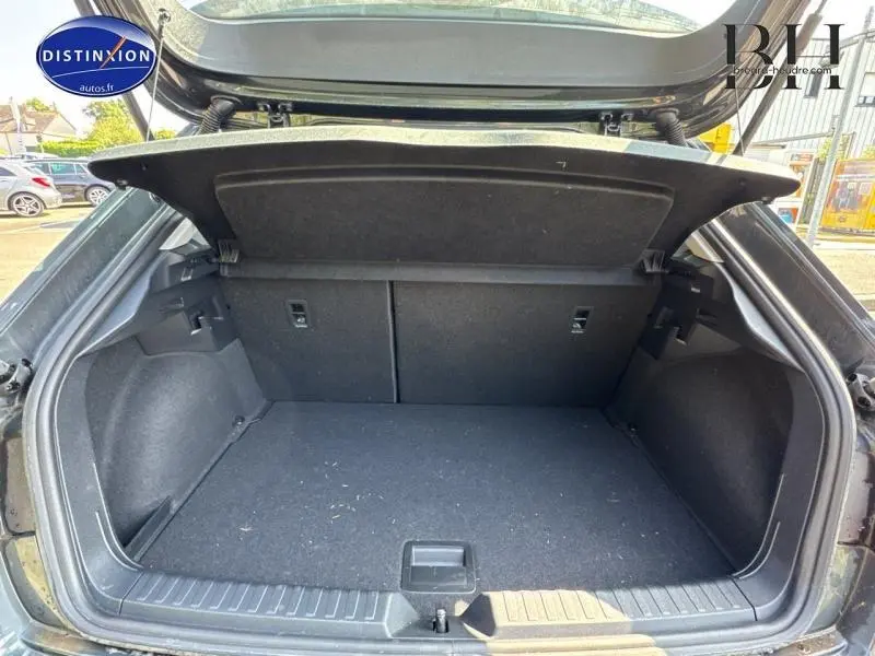 Coffre ouvert vu de l'arrière d'une Audi A1 Sportback 25 TFSI noir Mythic métallisé, intérieur spacieux et tapis noir.