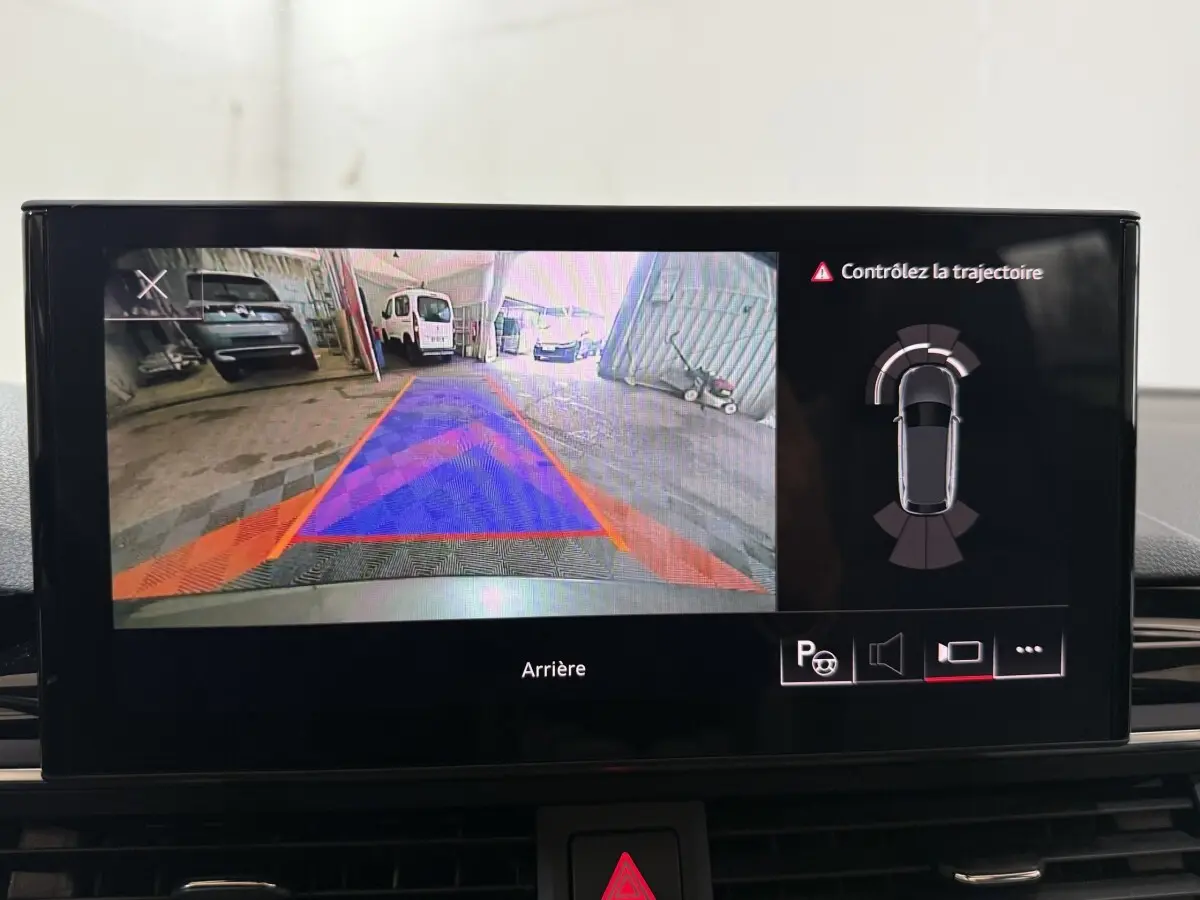 Écran multimédia montrant la caméra de recul avec guidage et alertes sur Audi A4 gris foncé, vue intérieure.