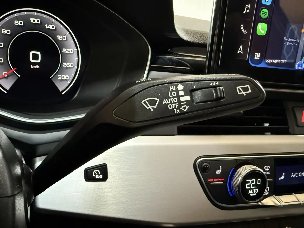 Gros plan sur le commodo d’essuie-glace et le tableau de bord numérique d’une Audi A4 gris foncé, intérieur moderne.