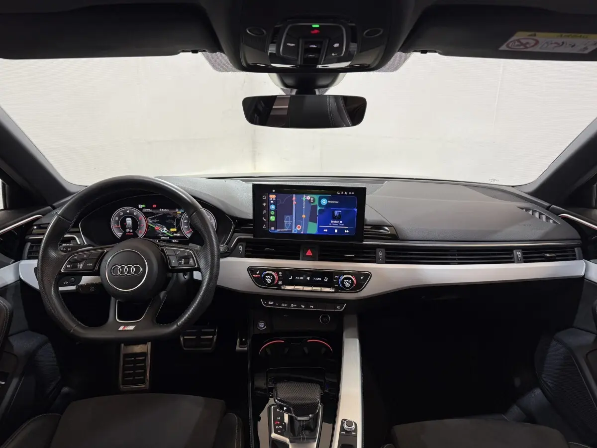 Vue intérieure avant de l'Audi A4 35 TFSI S Edition 2022, tableau de bord noir avec écran tactile central et volant cuir multifonctions.
