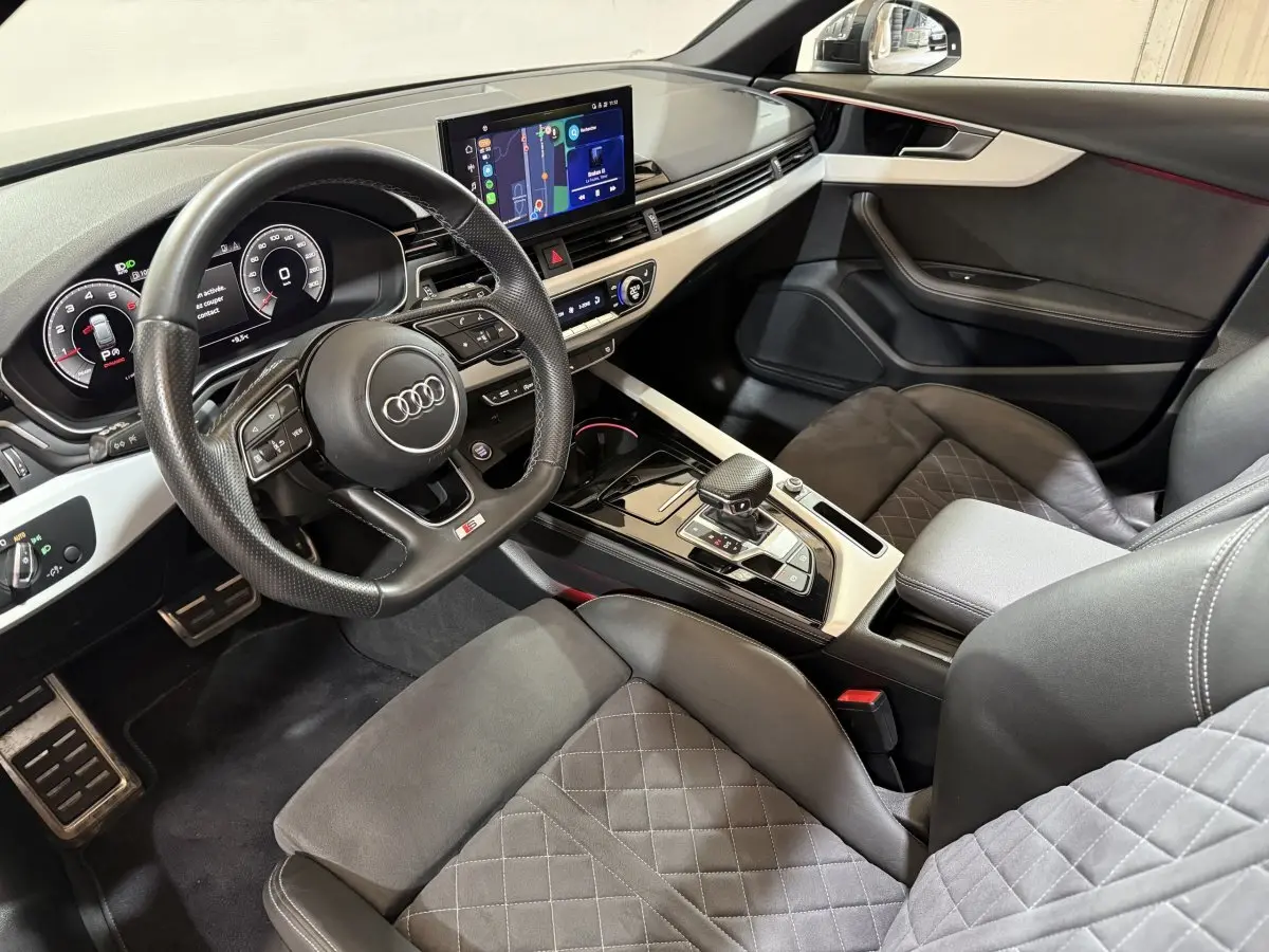 Vue intérieure côté conducteur de l'Audi A4 gris foncé avec tableau de bord numérique et écran tactile central.