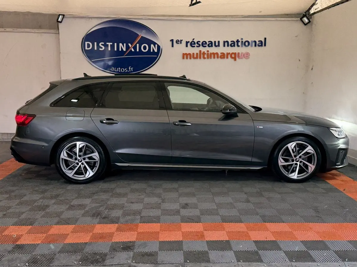 Vue de profil côté gauche d'une Audi A4 gris foncé break 35 TFSI S Edition en intérieur avec jantes alliage et toit ouvrant.