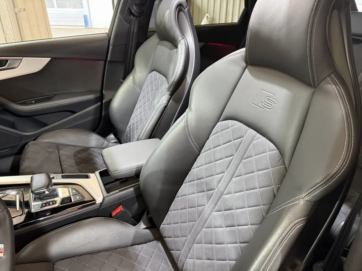 Vue intérieure rapprochée des sièges avant cuir gris foncé avec surpiqûres et logo S sur l’appui-tête de l’Audi A4.