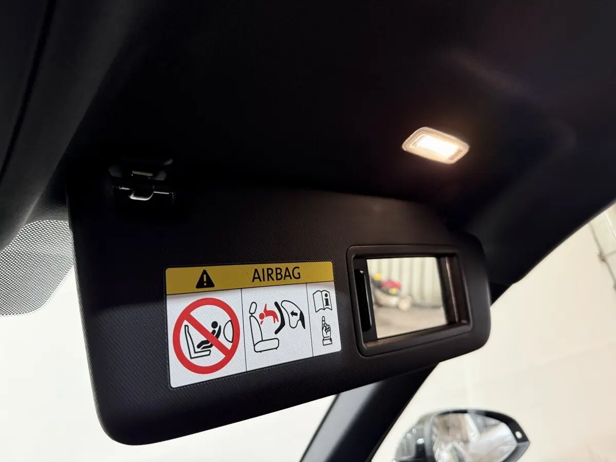 Détail du pare-soleil côté conducteur avec miroir éclairé et avertissement airbag dans un Audi A4 gris foncé 2022.