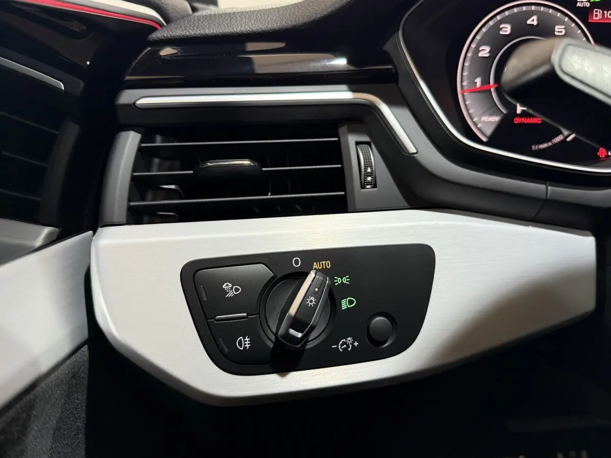 Détail du tableau de bord côté gauche de l’Audi A4 2022, avec commande d’éclairage en mode automatique sur fond gris clair.