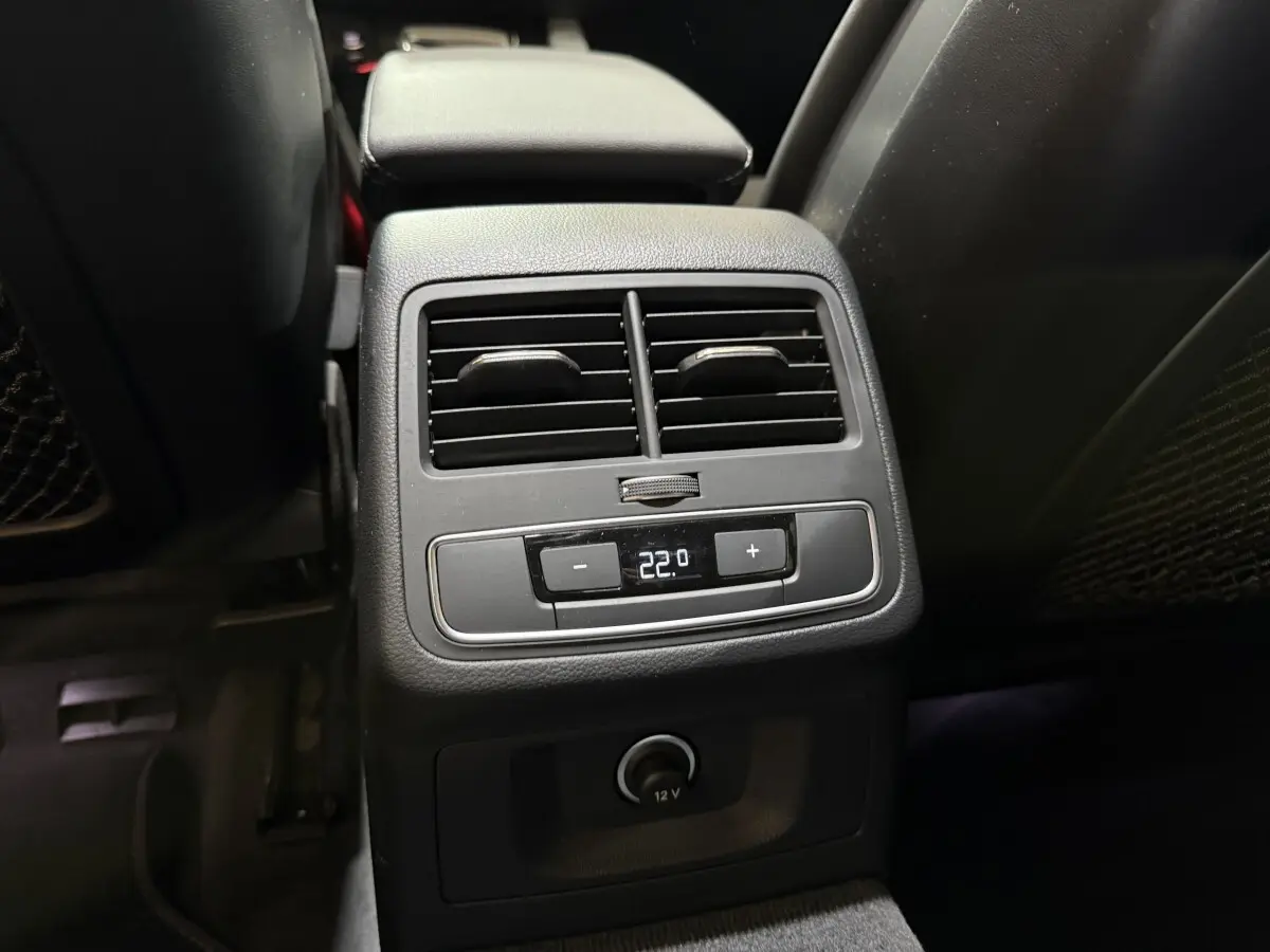 Vue rapprochée de la console arrière noire de l'Audi A4 35 TFSI 2022 avec commandes climatisation et prise 12V.