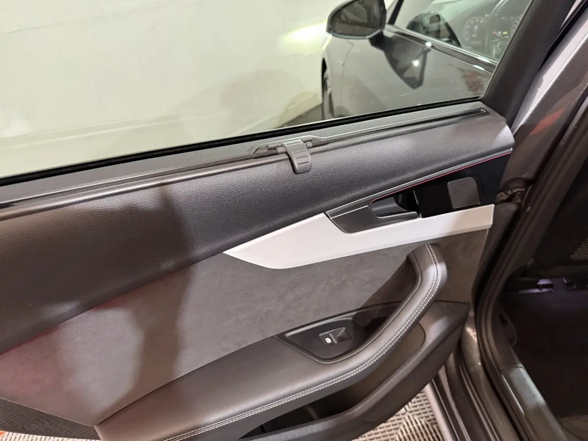 Vue intérieure du panneau de porte arrière droite gris foncé de l'Audi A4 35 TFSI avec insert argenté et commande de vitre.