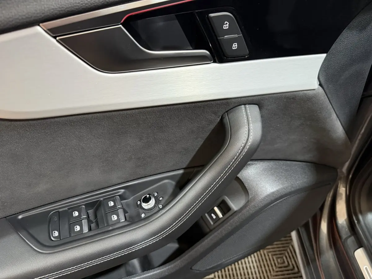 Gros plan sur la porte avant gauche gris foncé d’Audi A4 avec commandes des vitres et verrouillage.