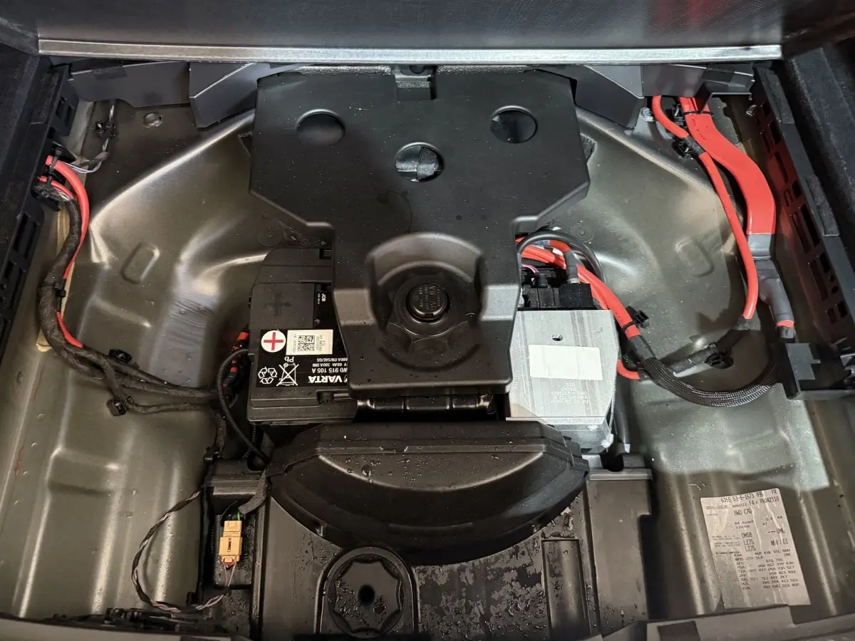 Vue plongeante sur le compartiment batterie gris métallique avec câbles rouges d’une Audi A4 35 TFSI hybride 2022.