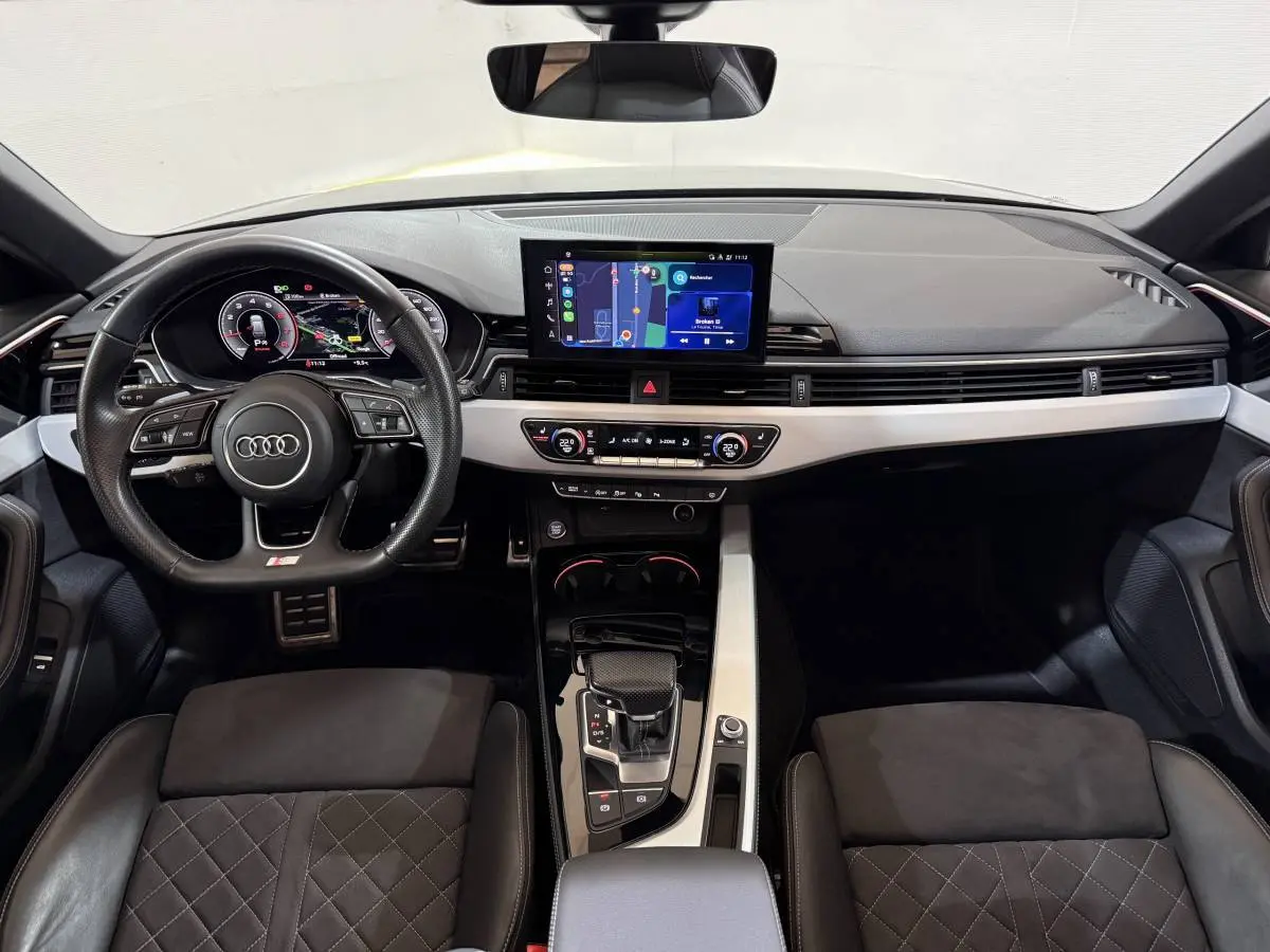 Vue intérieure avant de l'Audi A4 gris foncé 35 TFSI avec tableau de bord digital et écran tactile central.