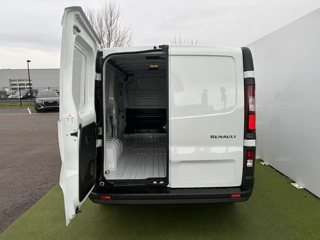 Vue arrière du Renault Trafic Fourgon blanc Glacier 2025 avec porte gauche ouverte montrant l'intérieur vide du coffre.
