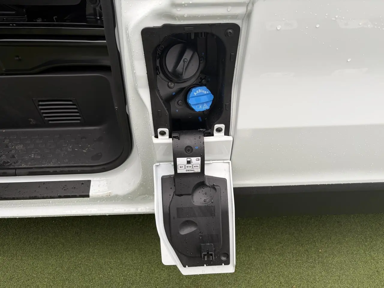 Gros plan sur la trappe à carburant ouverte côté gauche du Renault Trafic blanc glacier, avec bouchon AdBlue visible.