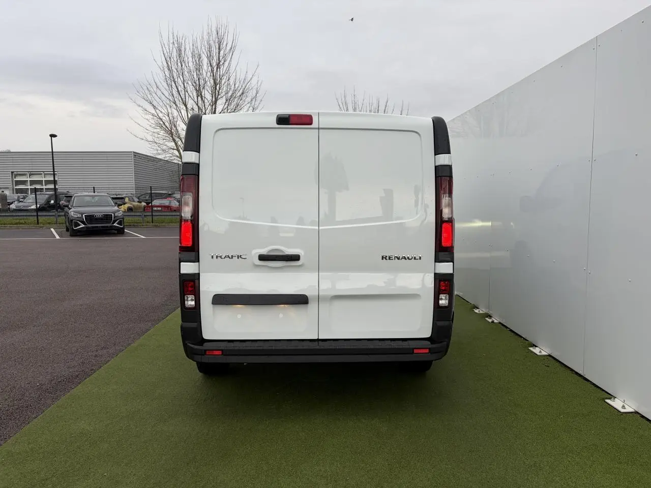 Vue arrière du Renault Trafic Fourgon blanc glacier avec portes arrière tôlées et feux verticaux allumés.