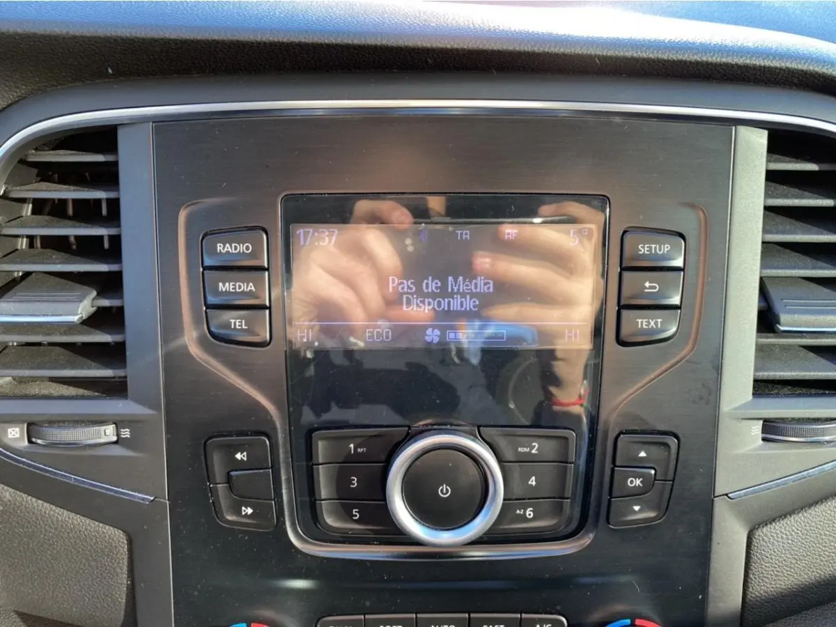Vue rapprochée du tableau de bord de la Renault Mégane gris platine, avec écran central et commandes audio visibles.