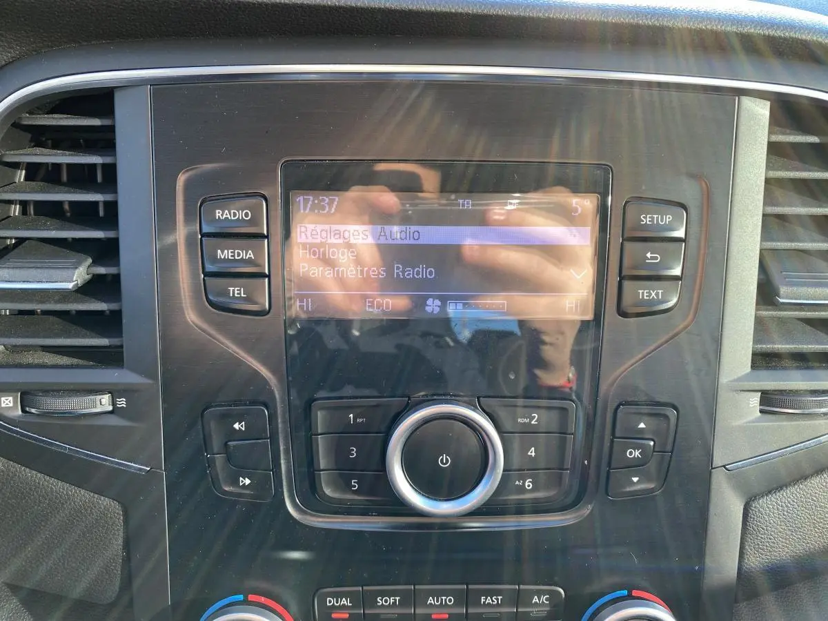 Vue rapprochée du tableau de bord de la Renault Mégane 2017, écran central avec réglages audio et commandes autour.