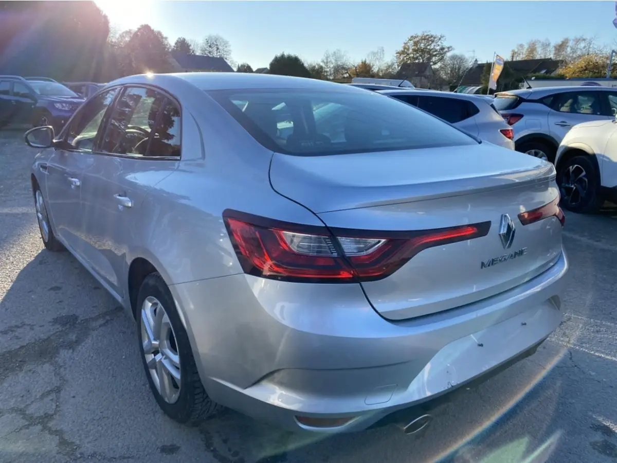 Vue 3/4 arrière droite d'une Renault Mégane Sedan gris platine 2017 avec feux arrière LED et hayon lisse.