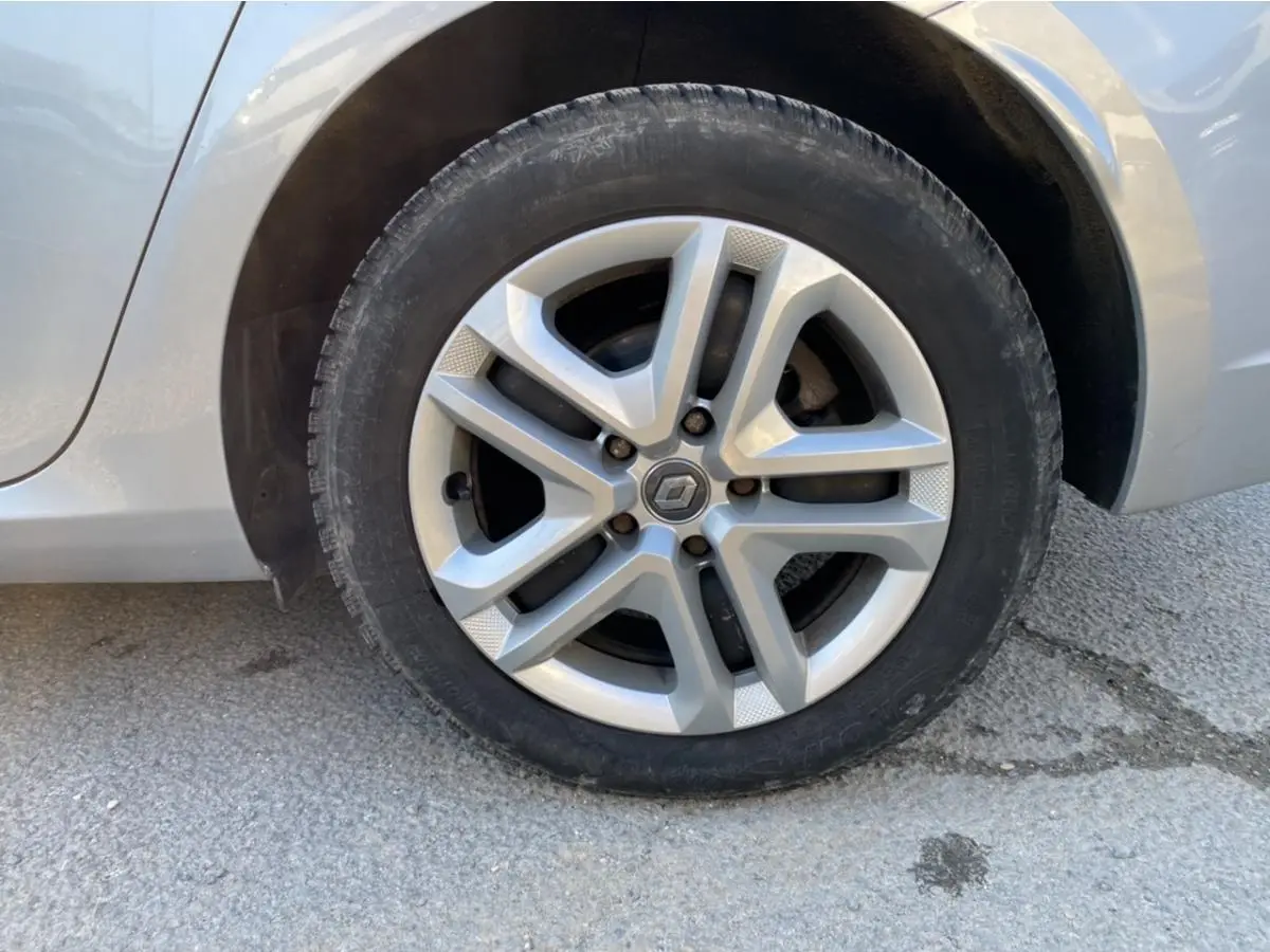 Gros plan sur la roue avant gauche de la Renault Mégane gris platine, avec jante alliage à cinq branches doubles.