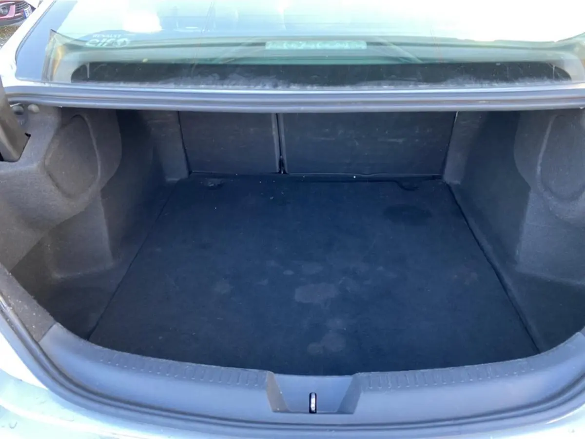 Coffre ouvert vu de l'arrière d'une Renault Mégane Sedan gris platine, montrant un espace de rangement vide.