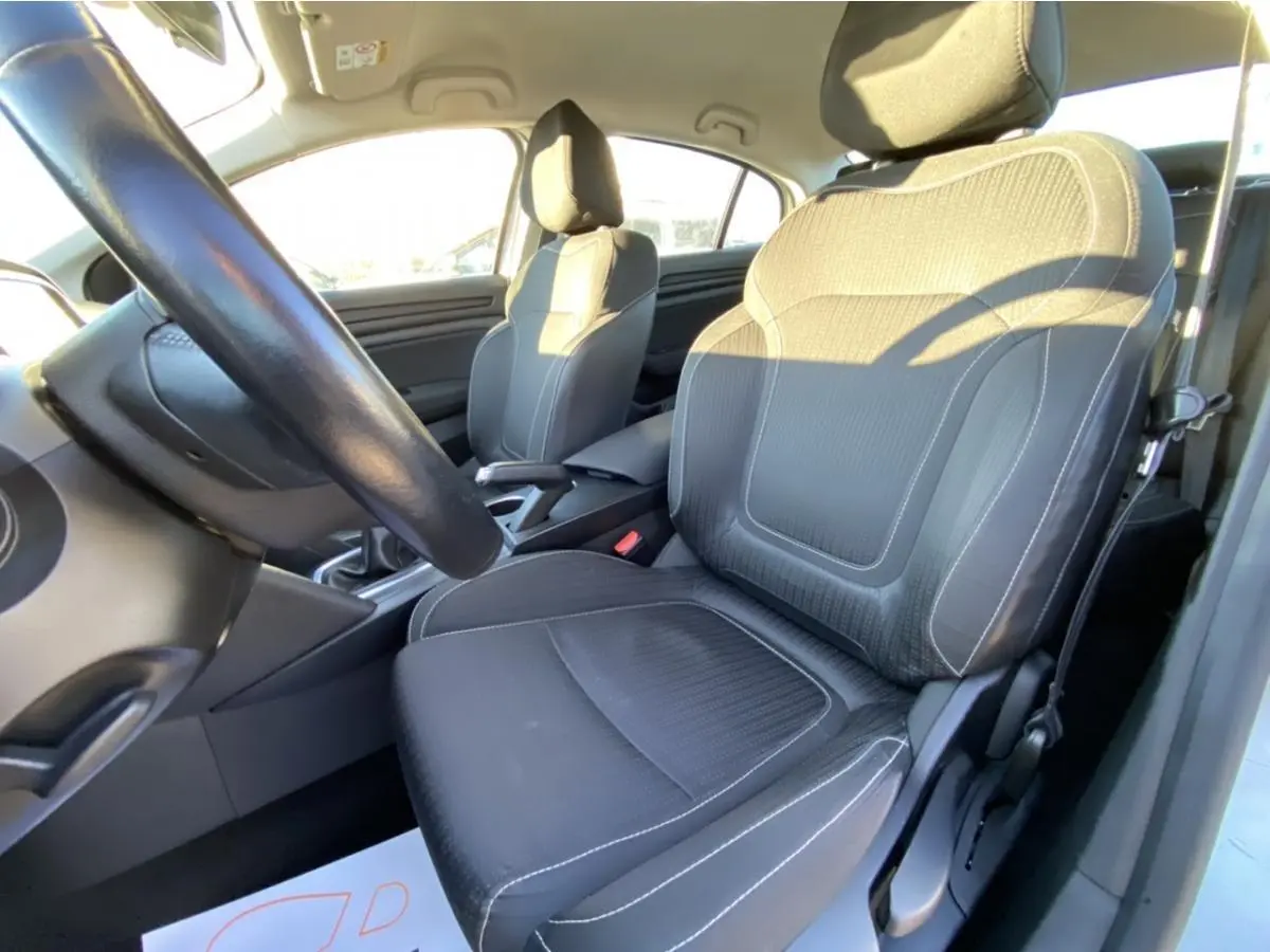 Vue intérieure côté conducteur de la Renault Mégane Sedan 2017, sièges noirs avec surpiqûres blanches et volant visible.