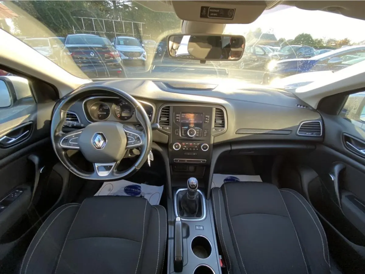 Vue intérieure avant de la Renault Mégane gris platine, tableau de bord avec volant multifonction et boîte manuelle.