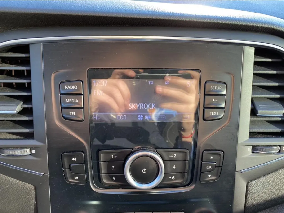 Tableau de bord de Renault Mégane gris platine, zoom sur l'écran central avec commandes radio et climatisation.
