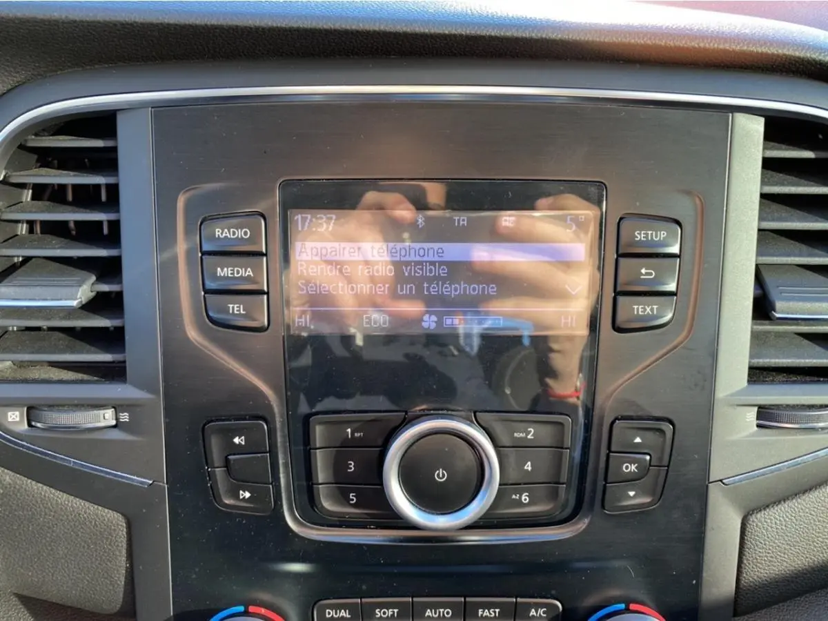 Vue rapprochée de la console centrale de la Renault Mégane 2017, écran tactile avec commandes radio et climatisation.