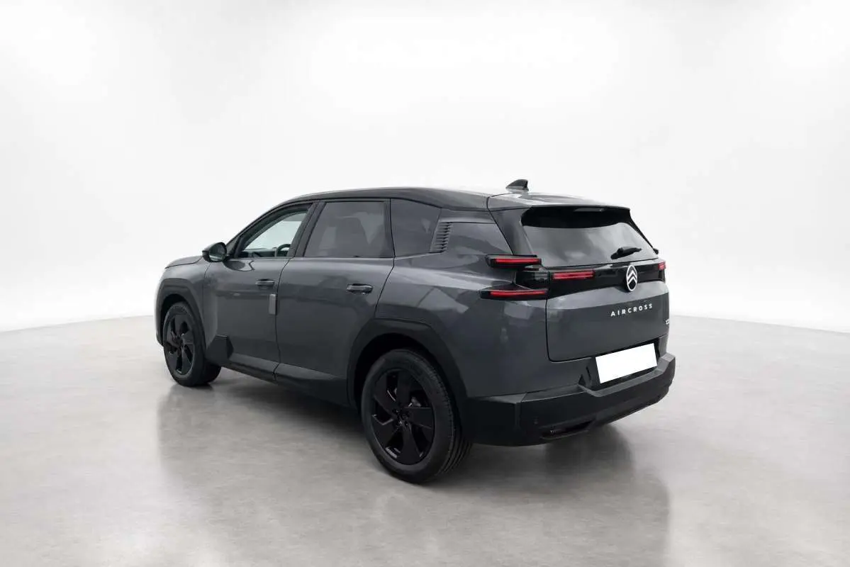 Vue 3/4 arrière droit du Citroën C5 Aircross gris foncé avec toit noir et jantes noires dans un studio blanc.
