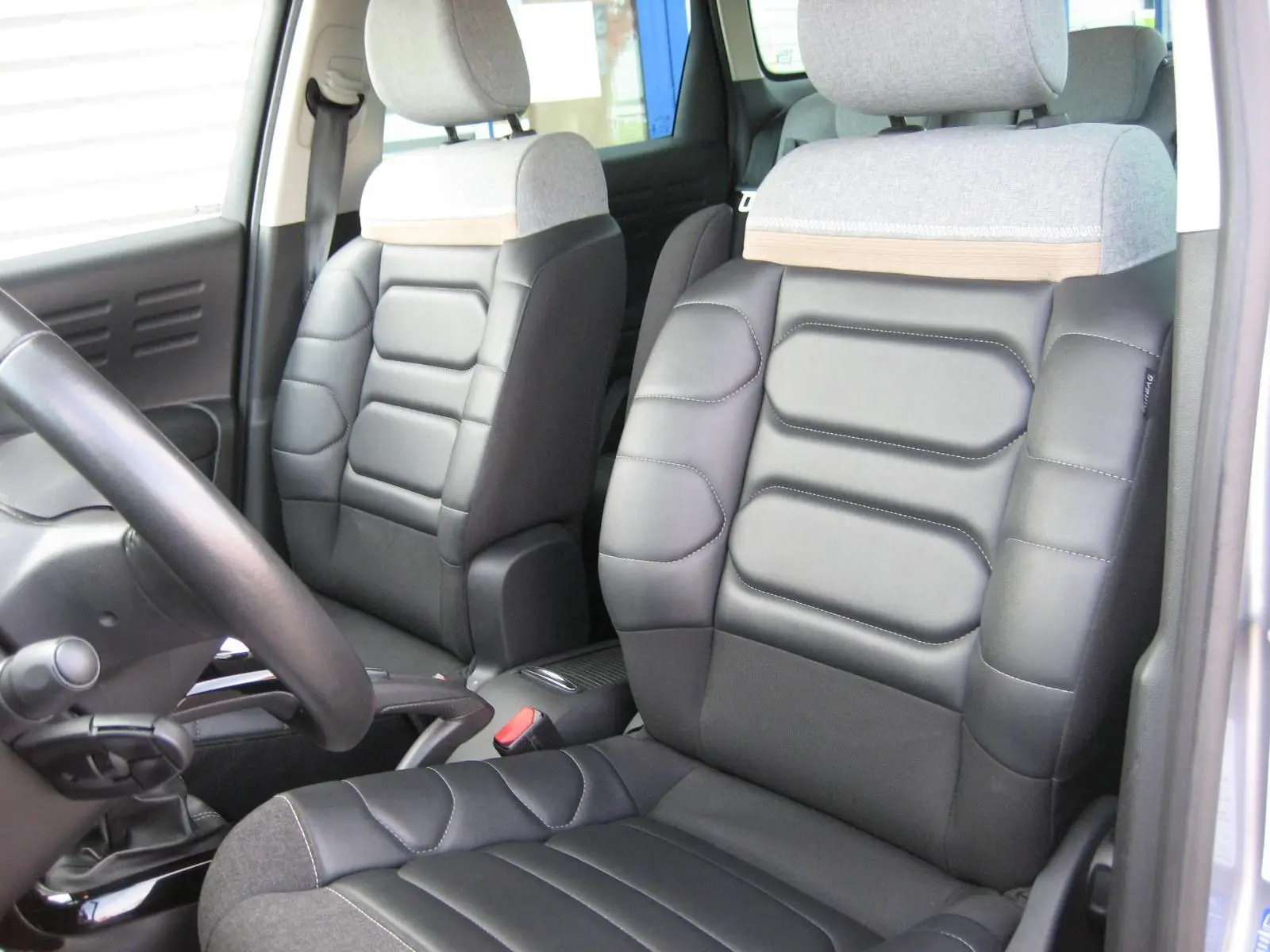 Intérieur du Citroën C3 Aircross gris platinium, vue rapprochée des sièges avant en cuir noir et tissu gris.