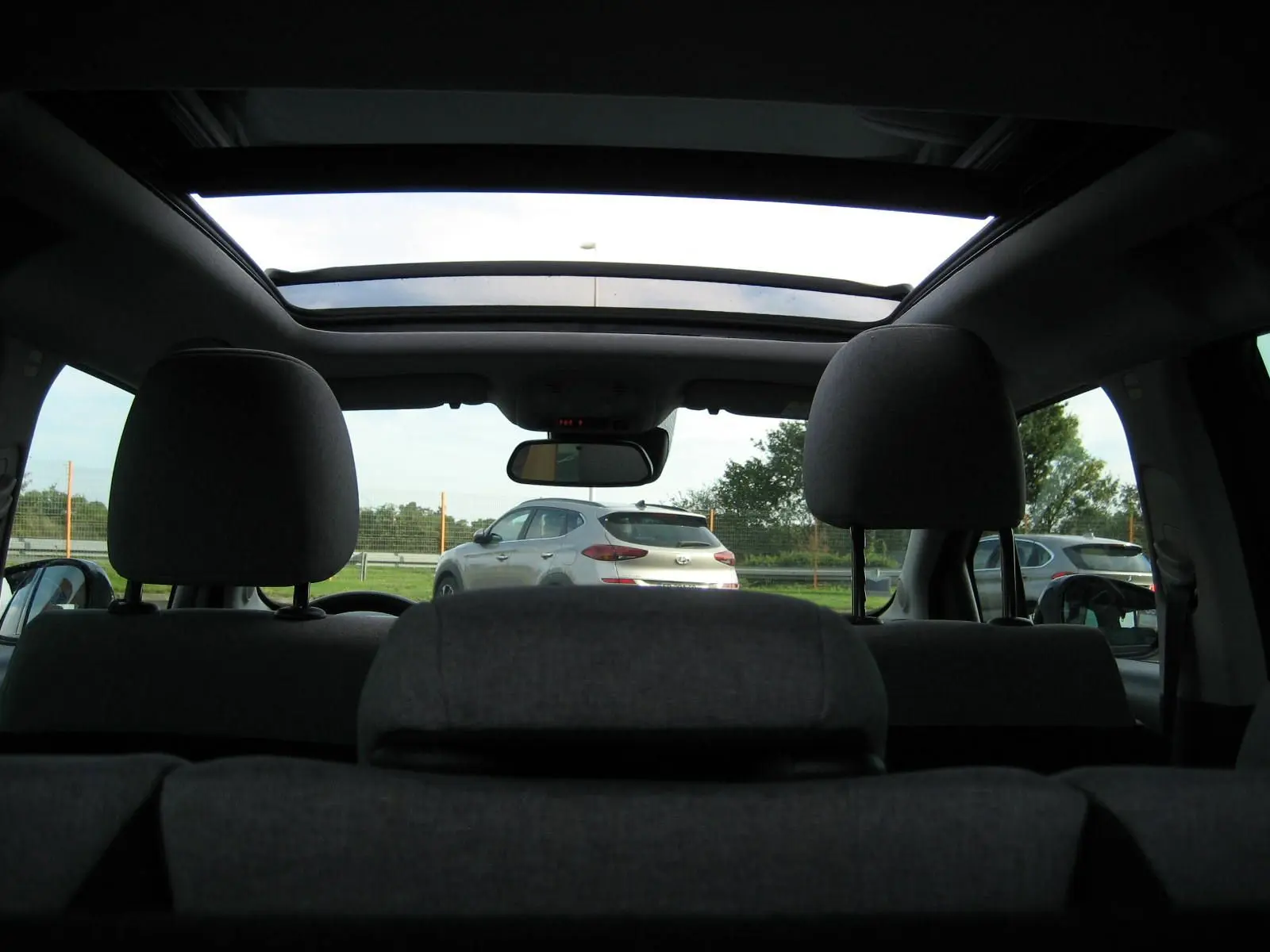 Vue intérieure arrière montrant le toit ouvrant panoramique et les appuie-têtes du Citroën C3 Aircross gris platinium.