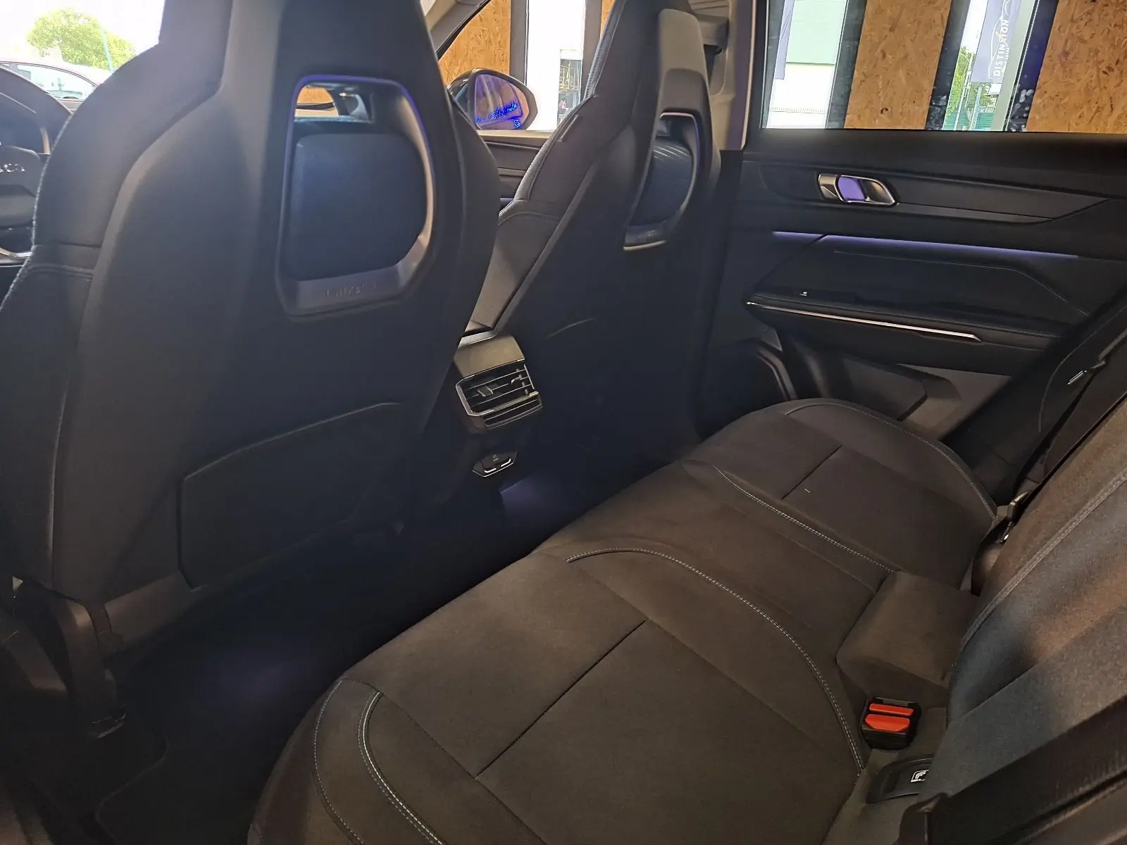 Vue arrière intérieure du Lynk & Co 01 hybride rechargeable 2023, sièges arrière en tissu noir avec éclairage d'ambiance.