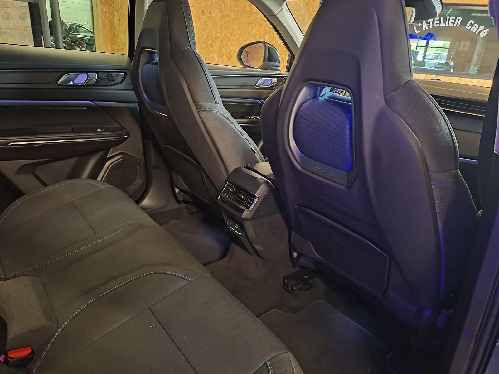 Vue intérieure arrière côté droit du LYNK & CO 01 noir, sièges en tissu noir avec surpiqûres bleues et éclairage d'ambiance bleu.