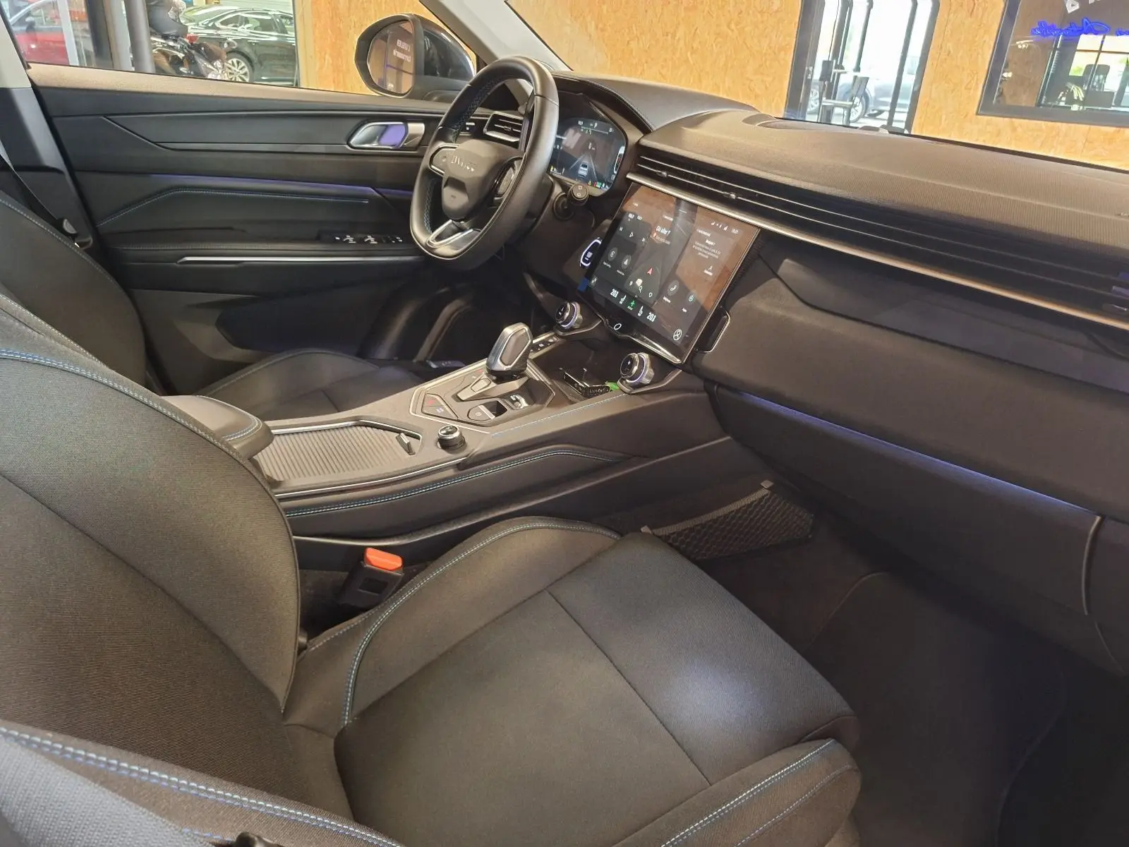 Vue intérieure côté conducteur du Lynk & Co 01 hybride rechargeable noir 2023 avec écran tactile et sellerie tissu noir.