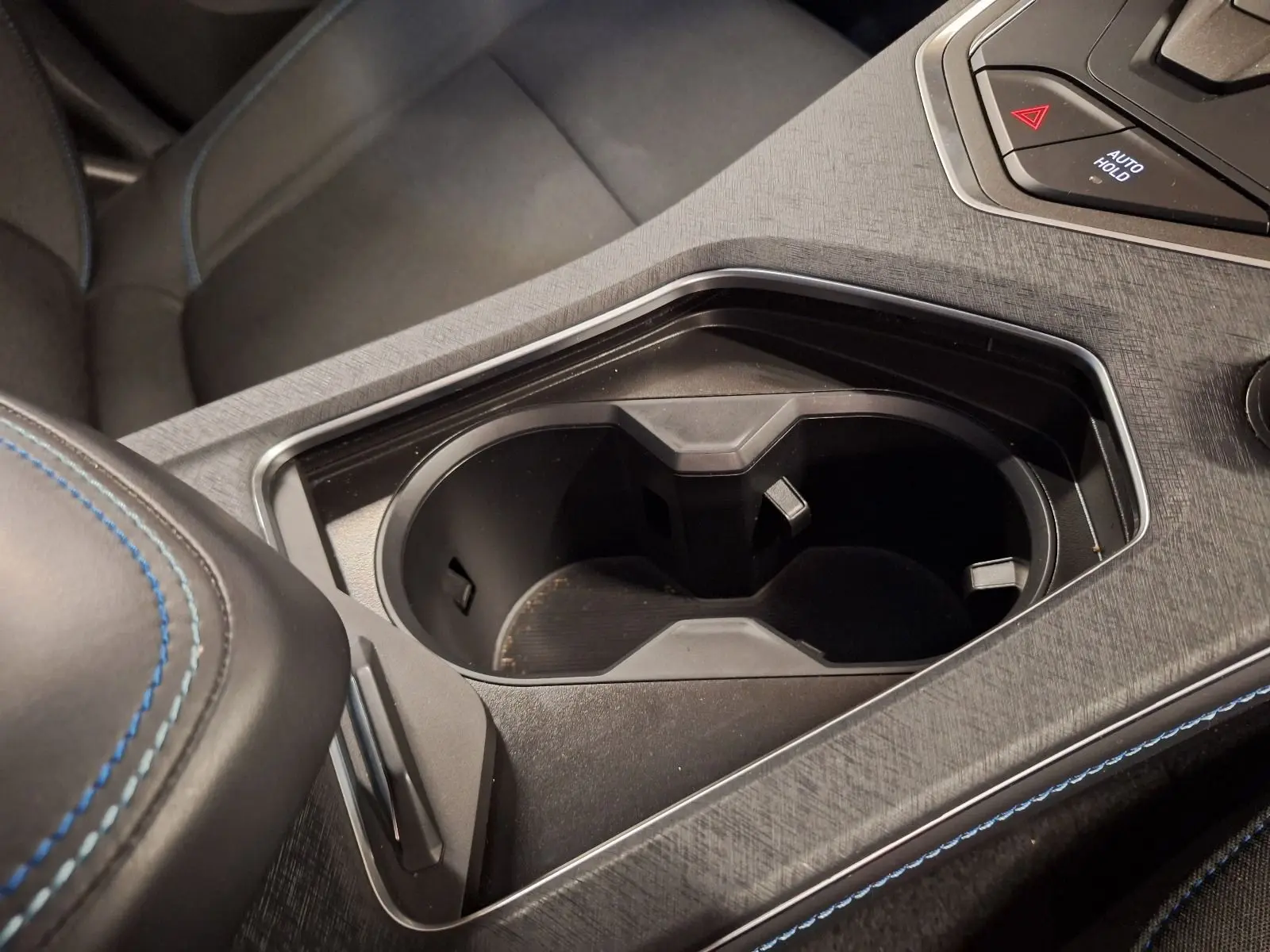 Gros plan sur le porte-gobelets central noir et la console avec surpiqûres bleues à l'intérieur du Lynk & Co 01 hybride 2023.