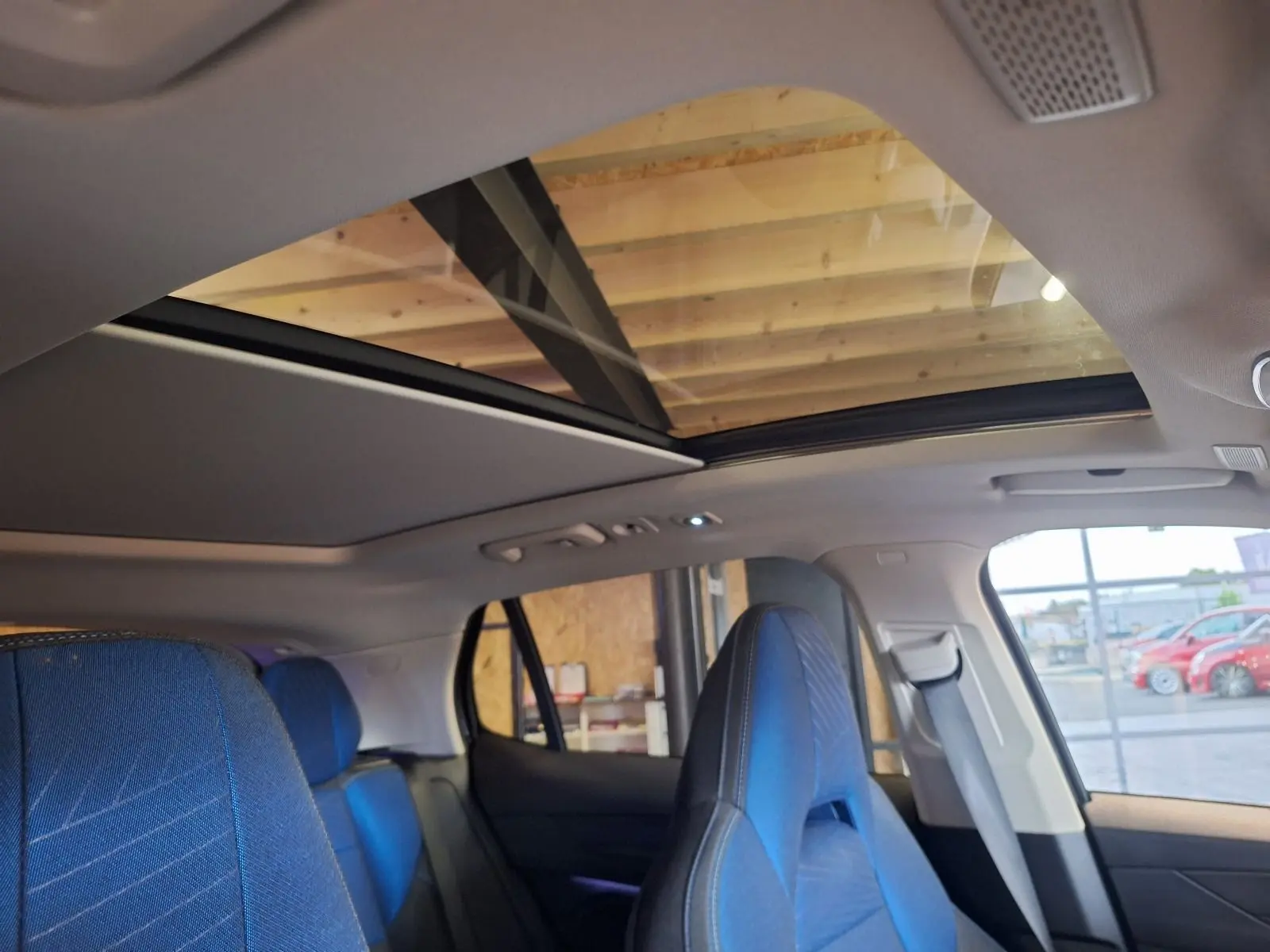 Intérieur du LYNK & CO 01 noir, vue sur les sièges avant et arrière en tissu bleu avec toit panoramique ouvert.