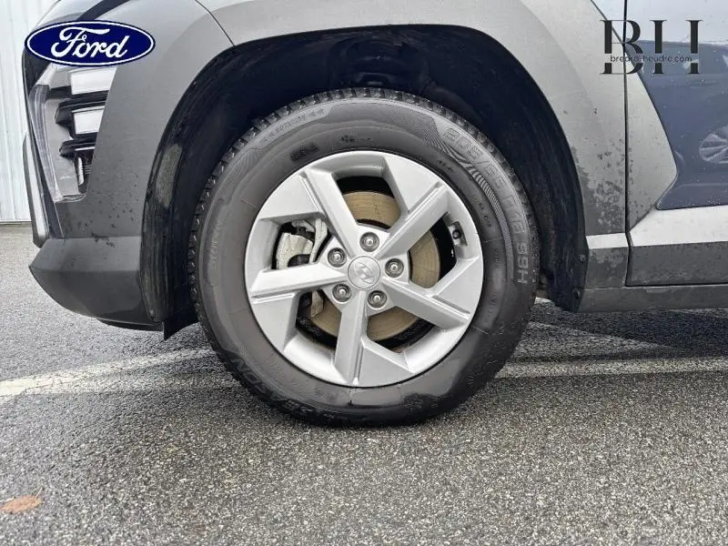 Gros plan sur la roue avant gauche d'un Hyundai Kona 2023 Denim Blue perlé métallisé avec jante alu cinq branches.