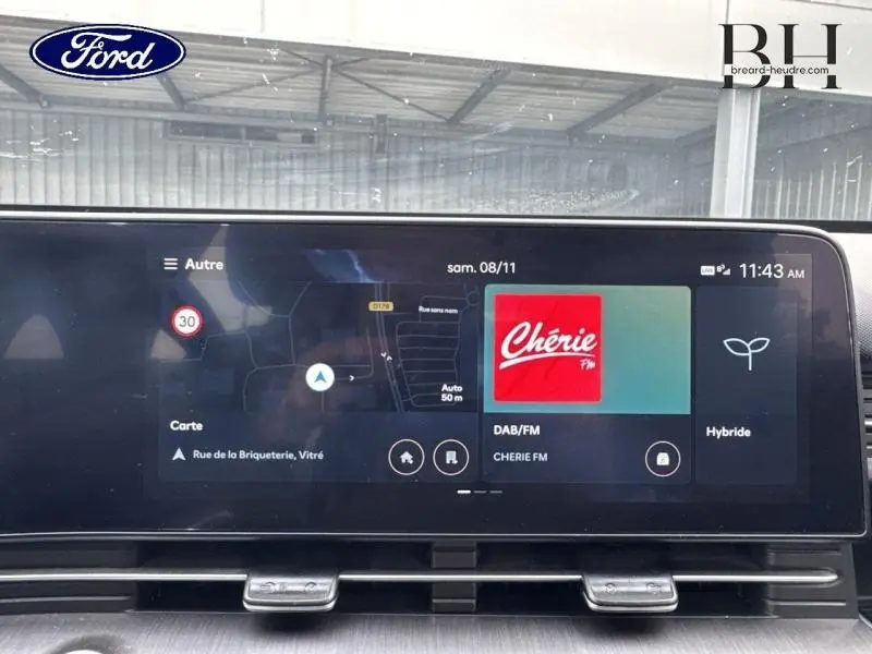 Écran tactile central du Hyundai Kona 2023 en Denim Blue, affichant GPS et radio Chérie FM en intérieur.