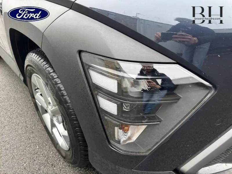 Gros plan sur le phare avant droit d'un Hyundai Kona 2023 Denim Blue perlé métallisé, avec jante alu visible.