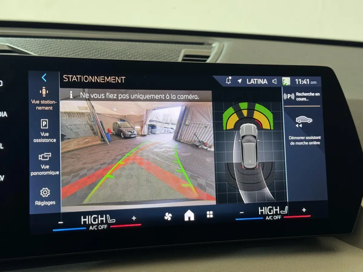 Écran tactile intérieur montrant l’aide au stationnement avec vue caméra arrière et capteurs du BMW X1 gris foncé 2024.