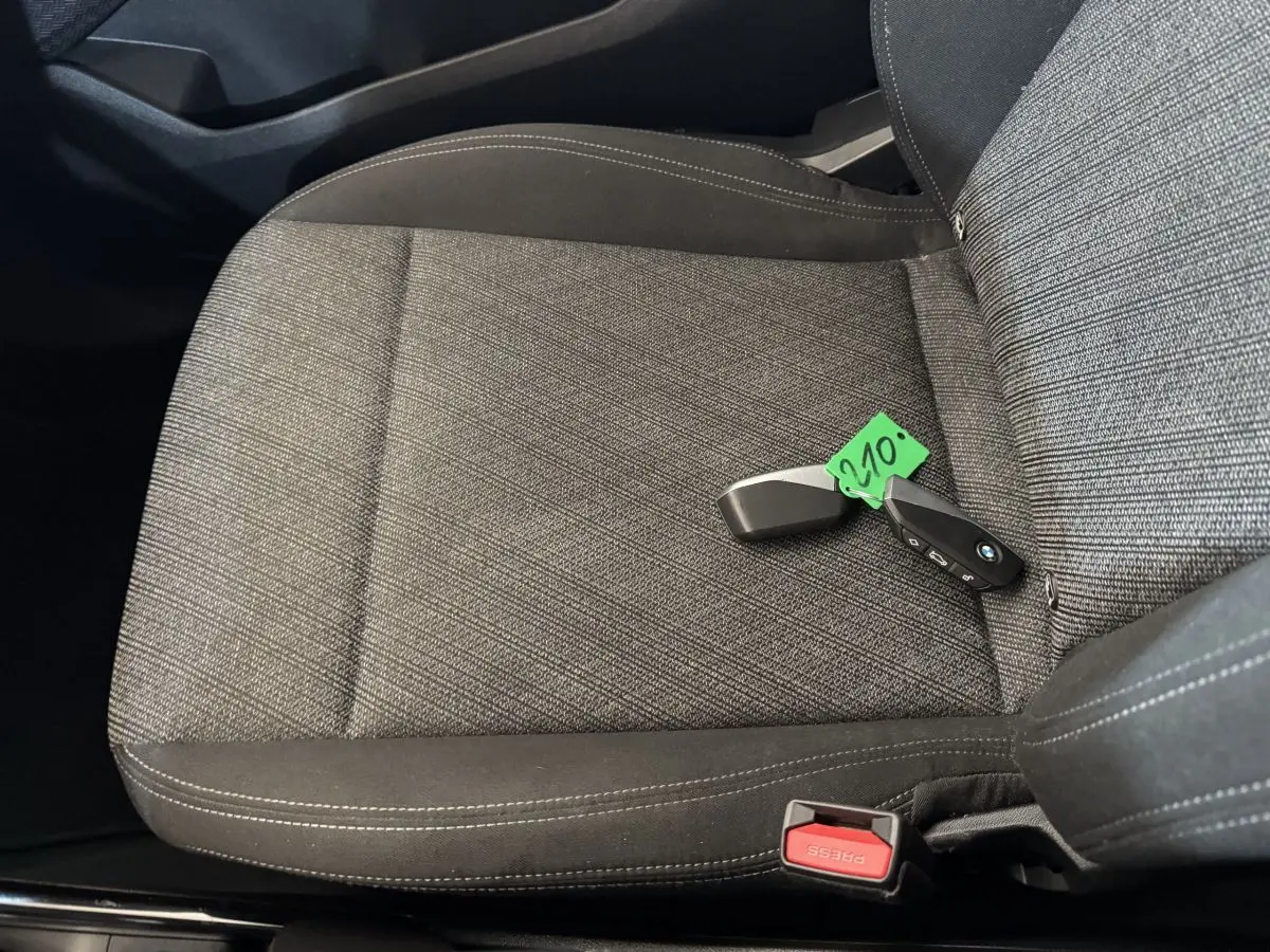 Gros plan sur le siège avant droit gris foncé du BMW X1 2024 avec clé et ceinture de sécurité visible.