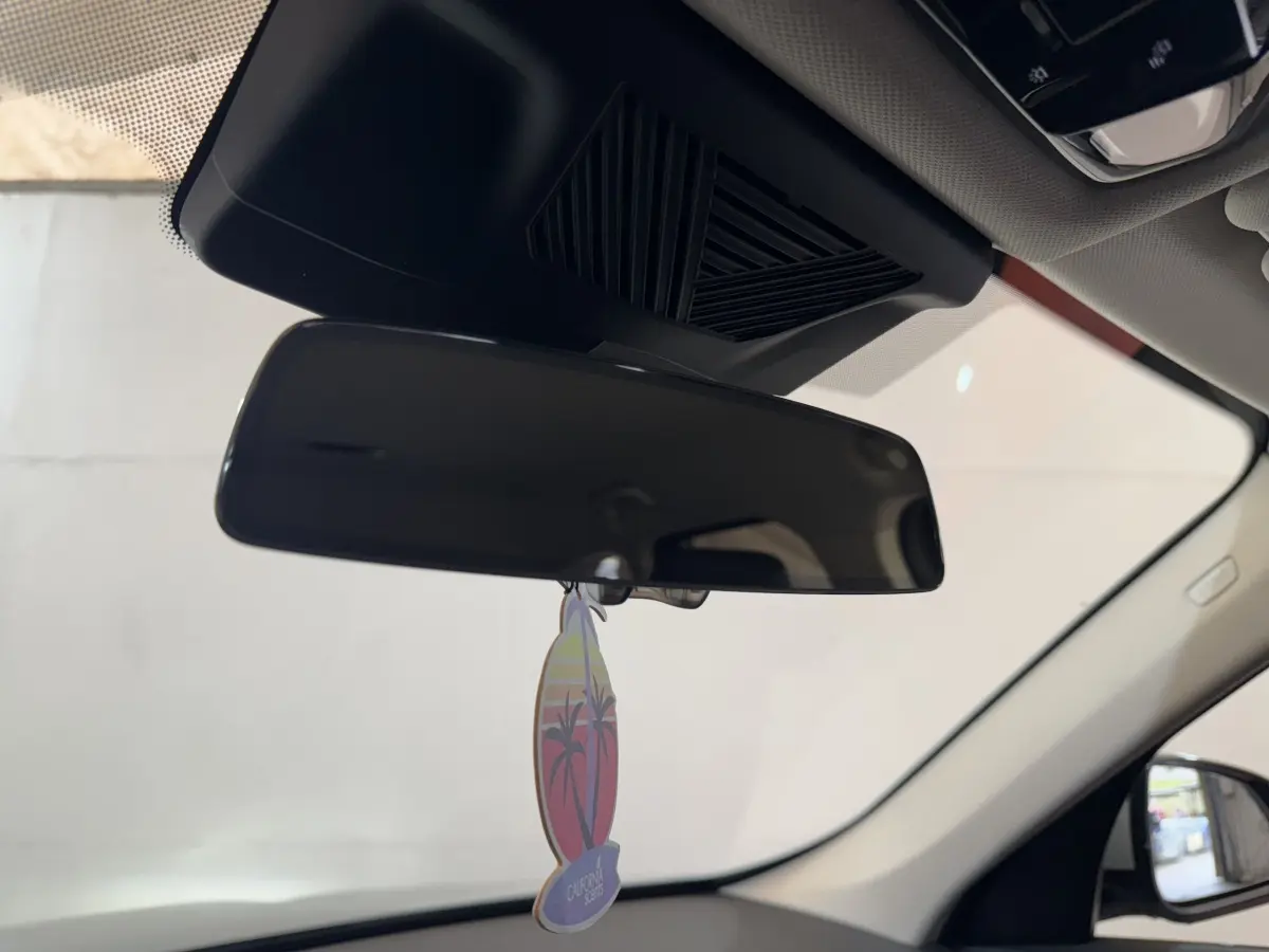 Vue intérieure centrée sur le rétroviseur intérieur noir avec un parfum suspendu dans un BMW X1 gris foncé 2024.