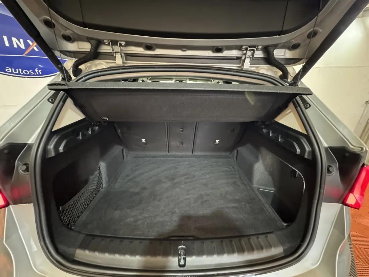 Vue arrière du coffre ouvert d’un BMW X1 gris foncé 2024, montrant un espace de chargement propre et spacieux.