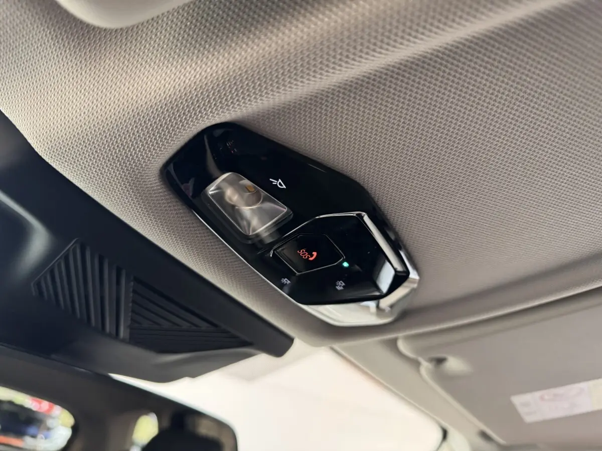 Vue intérieure en contre-plongée du plafonnier gris clair avec commandes d'éclairage et bouton SOS du BMW X1 2024.