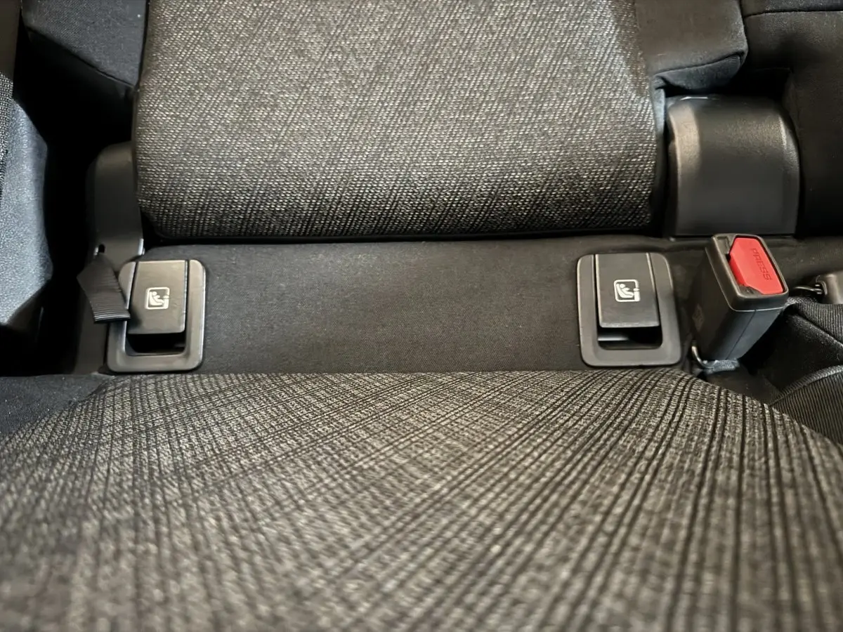 Gros plan sur la banquette arrière grise du BMW X1 2024, montrant les fixations Isofix et la boucle de ceinture.