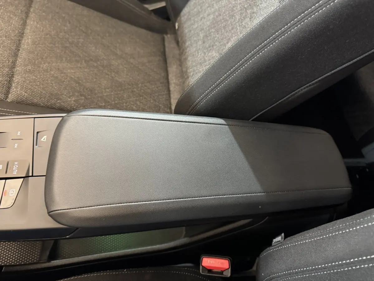 Gros plan sur l'accoudoir central noir et la console entre les sièges avant du BMW X1 gris foncé 2024.