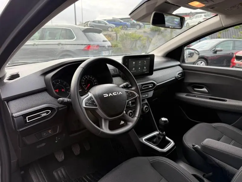 Vue intérieure côté conducteur du Dacia Jogger 2025, montrant le volant, tableau de bord et écran tactile central.