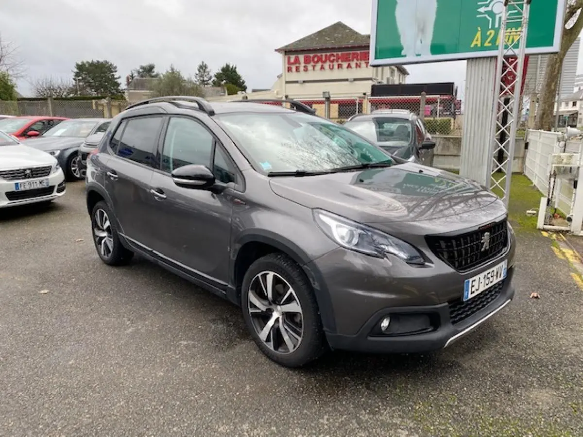 Peugeot 2008 gris platinium en 3/4 avant droit, avec jantes alliage 17 pouces noir brillant et barres de toit noires.