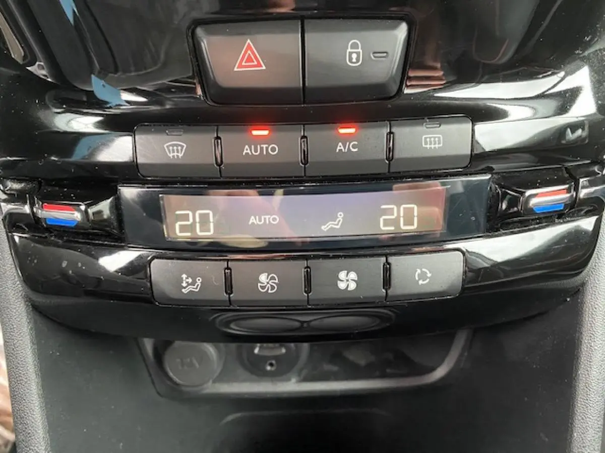Gros plan sur la console centrale noire brillante du Peugeot 2008, affichant la climatisation automatique bizone réglée à 20°C.