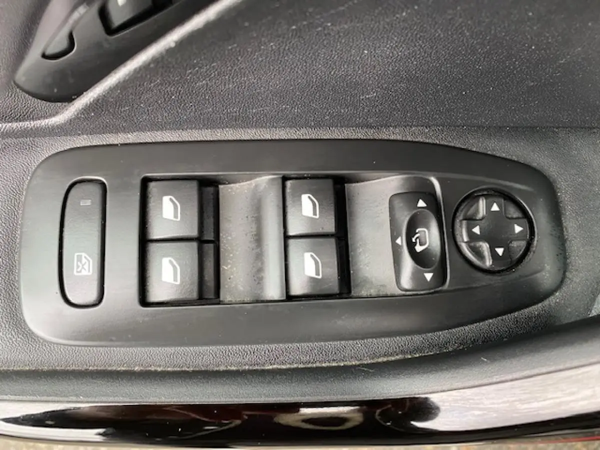 Gros plan sur les commandes des vitres et rétroviseurs côté conducteur d'une Peugeot 2008 gris platinium.