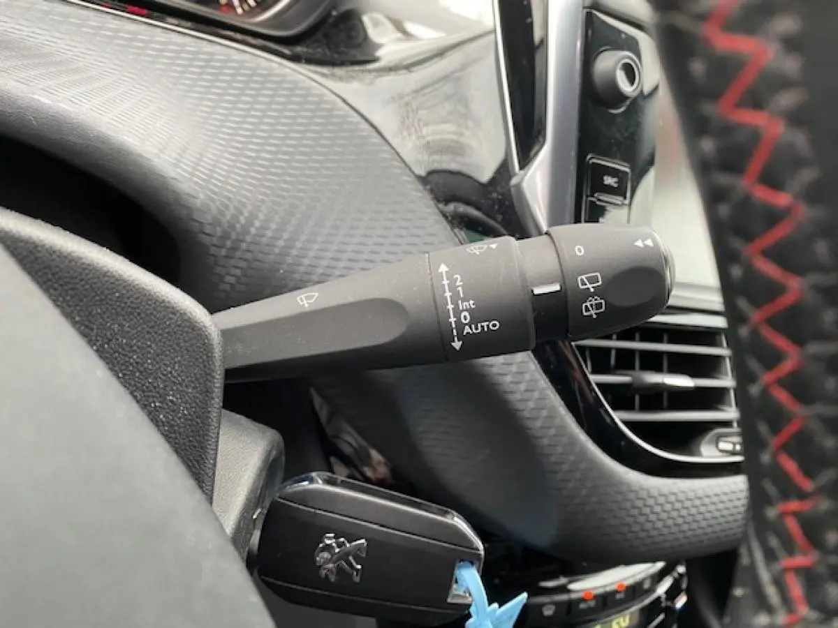 Gros plan sur la commande d'essuie-glace à gauche du volant dans l'habitacle du Peugeot 2008 gris platinium.